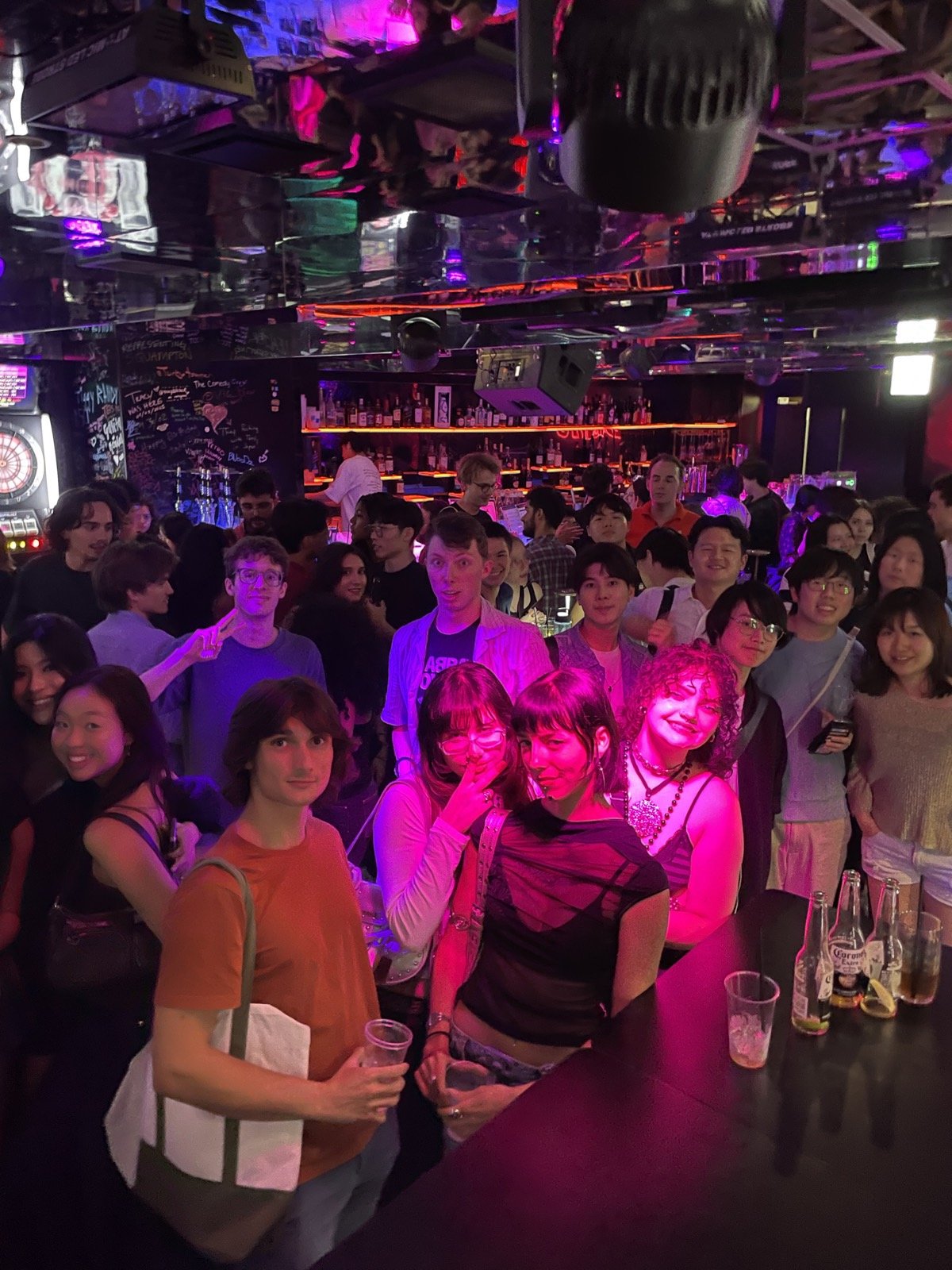 ピンクと紫のライトに照らされた、満員のフロアの参加者たち